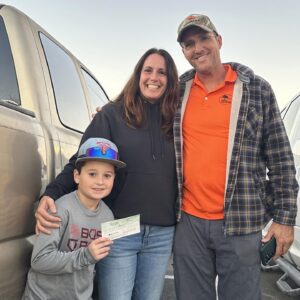 Photo of Dusty and Jen with young basball player presenting their support check