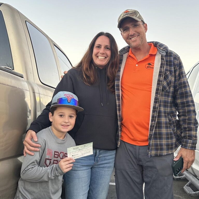 Photo of Dusty and Jen with young basball player presenting their support check