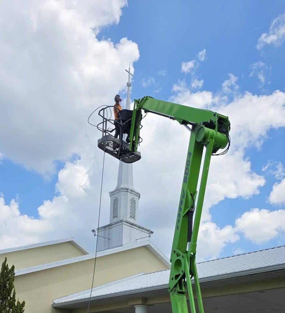 Close up of Dustys worker using boom lift to pressure wash steeple - boom lift services in dunnellon