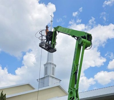 Close up of Dustys worker using boom lift to pressure wash steeple - boom lift services in dunnellon